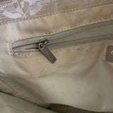Close-up of a beige bag with a zipper and visible brand name.