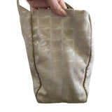 Side of Beige patterned bag held by a hand on a white background