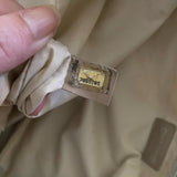 Close-up of a beige fabric with serial number and a hand holding it.