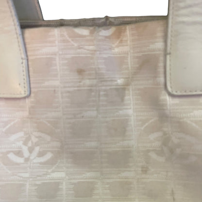 A close-up of a beige and off-white patterned handbag surface with visible scuffs, stains, and wear, showing part of the strap attachment and a faint repeating monogram-like pattern.