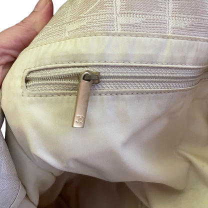 interior of purse with a zippered pocket with silver hardware showing a CC pattern with a hand holding