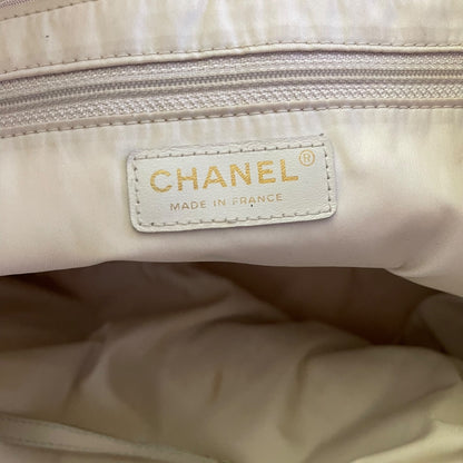 Interior of purse showing a zippered pocket and a off white beige Chanel leather patch. 