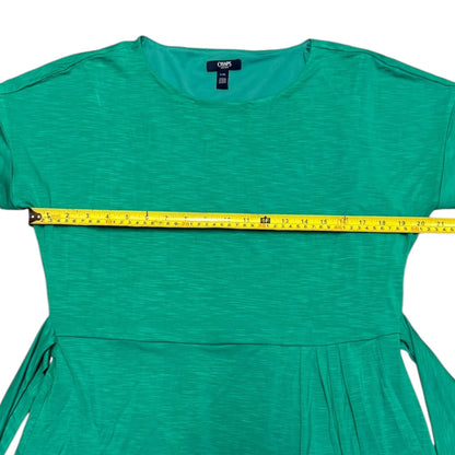 A green short-sleeve dress laid flat on a white background with a yellow measuring tape stretched horizontally across the chest to show the width.