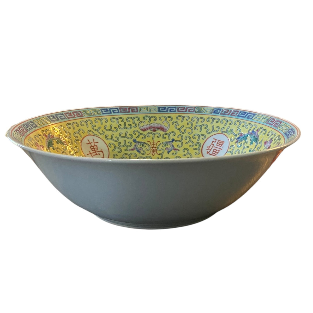 A large bowl with a white exterior and a highly decorated interior featuring a yellow patterned design with red Chinese characters and blue details.