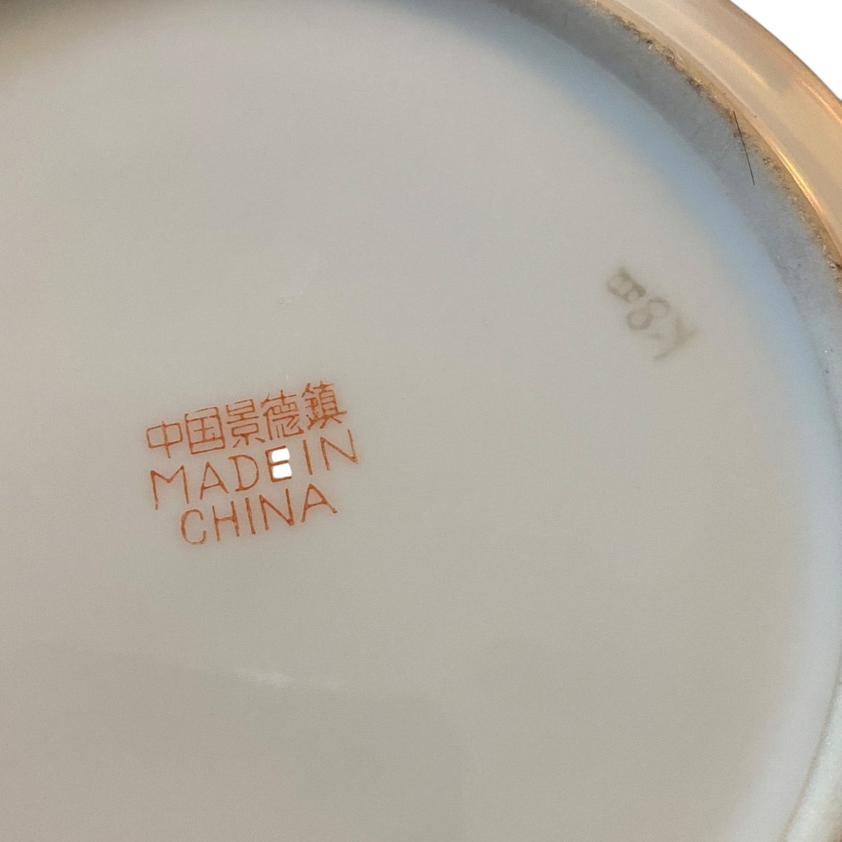 Close-up of the bottom of a white bowl, showing orange printed text reading '中国景德镇 MADE IN CHINA' and a gray mark reading 'K8X'.