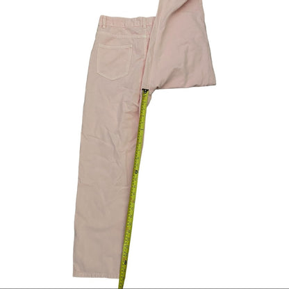 A pair of light pink pants laid flat on a white background, with a yellow measuring tape running vertically down the center to show the length.