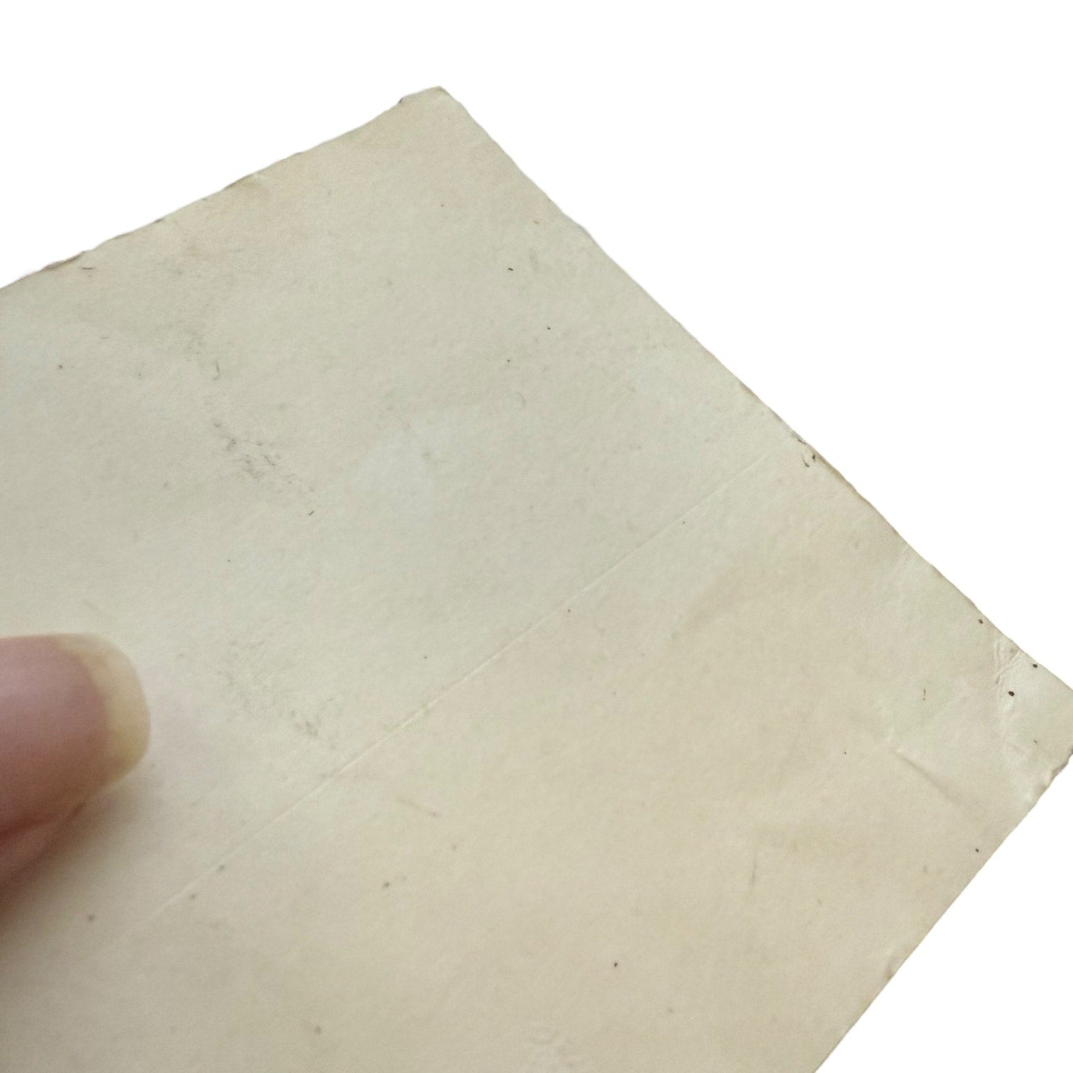 Back of sticker showing issues held by a finger on a white background