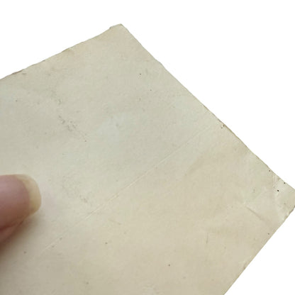 Back of sticker showing issues held by a finger on a white background