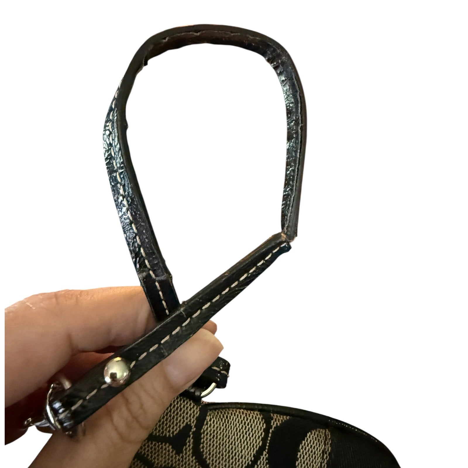 Black leather strap with damage held by a hand on a white background