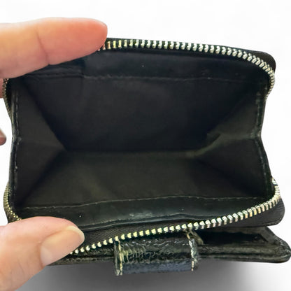 Black wallet with silver zipper held open by a hand on a white background