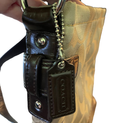 Black leather key fob with Coach logo attached to a camouflage bag.