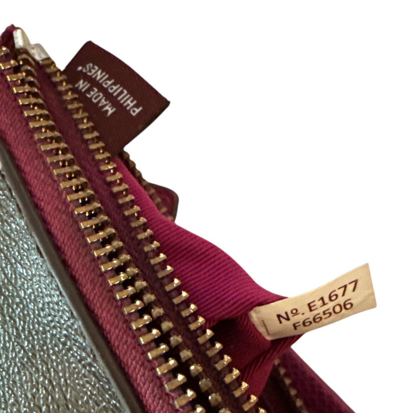 Close-up of a zipper pouch showing a  inner lining, gold-tone zipper, and a brown sewn-in tag reading 'MADE IN PHILIPPINES'.