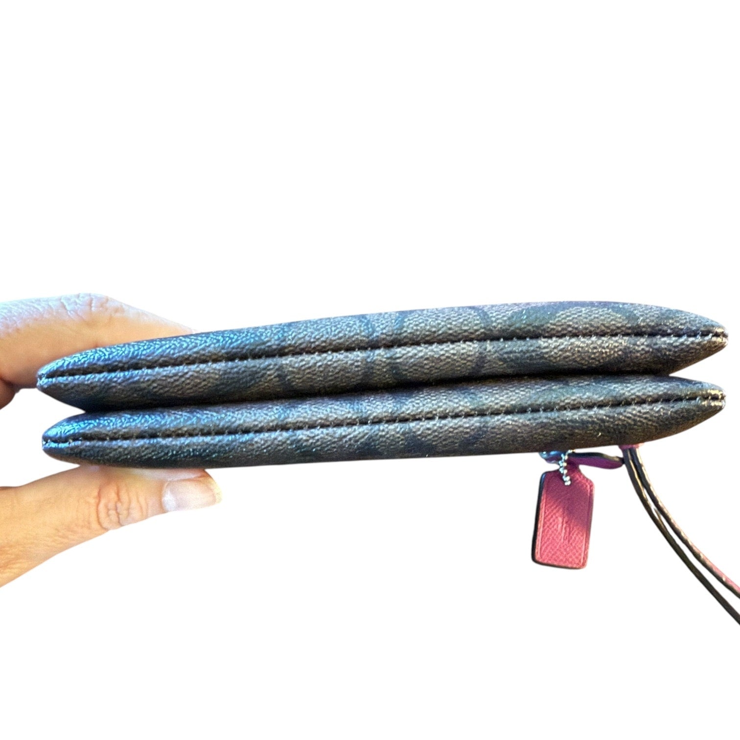 A close-up of a hand holding brown wristlet bottom edging, against a plain white background.