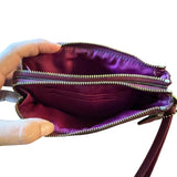 Interior of handbag with a zipper held open by a hand on a white background