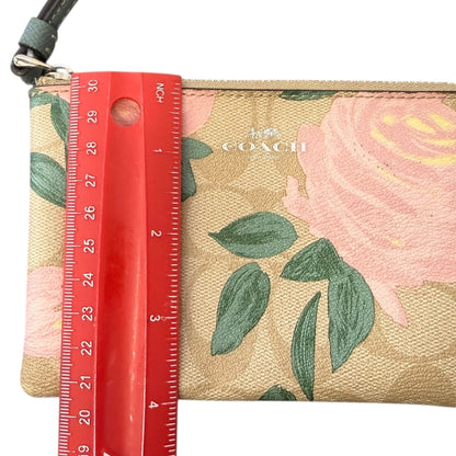 Coach wallet with floral design and a red ruler for size reference on a white background