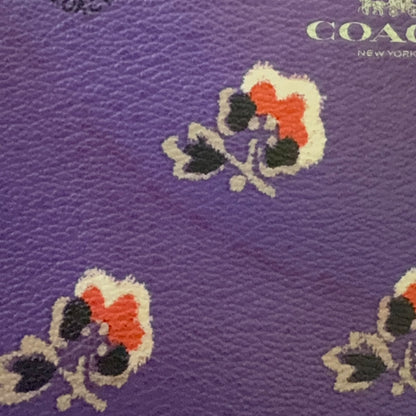 Purple wristlet with floral patterns and Coach branding showing issues