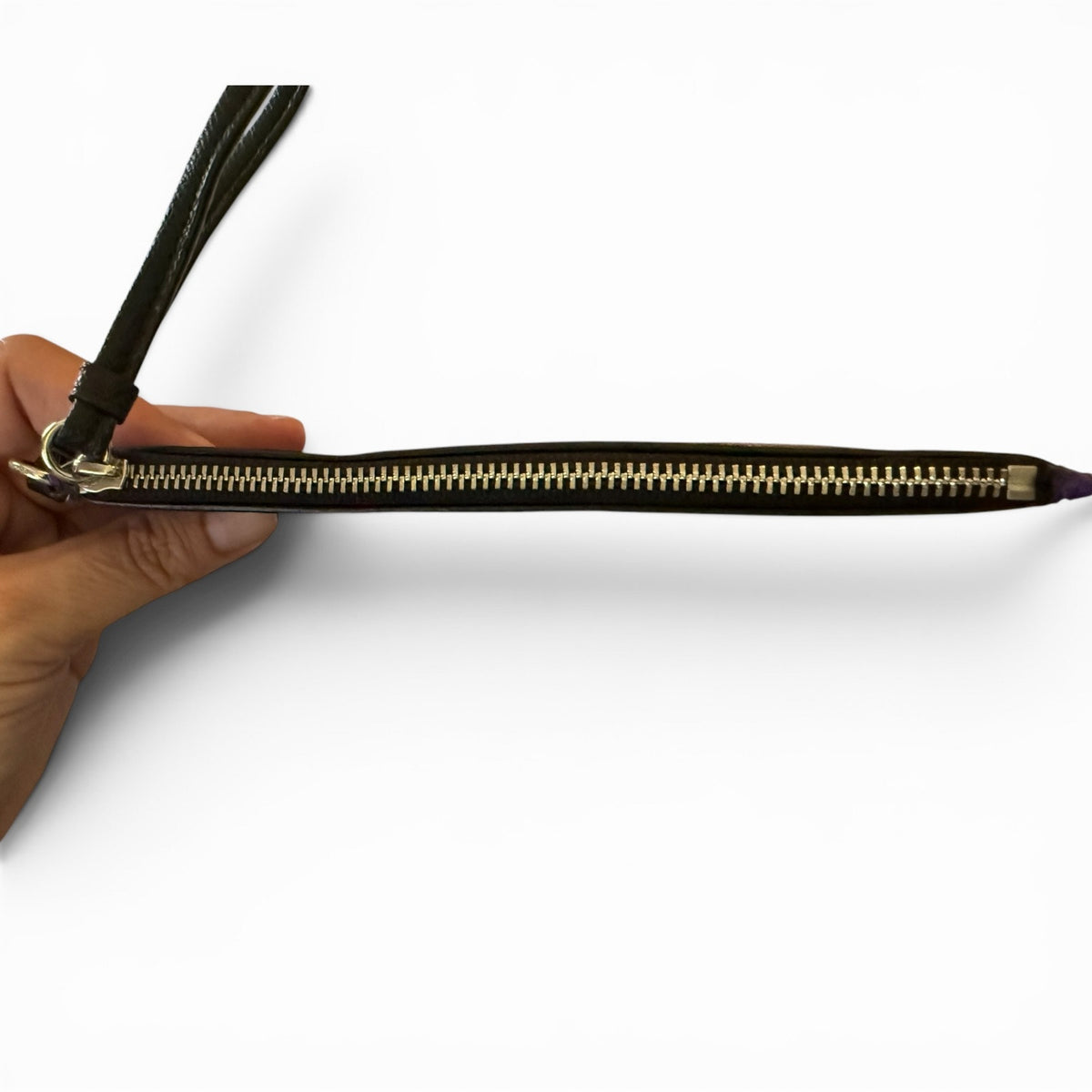 Hand holding a wristlet showing the top view against a white background