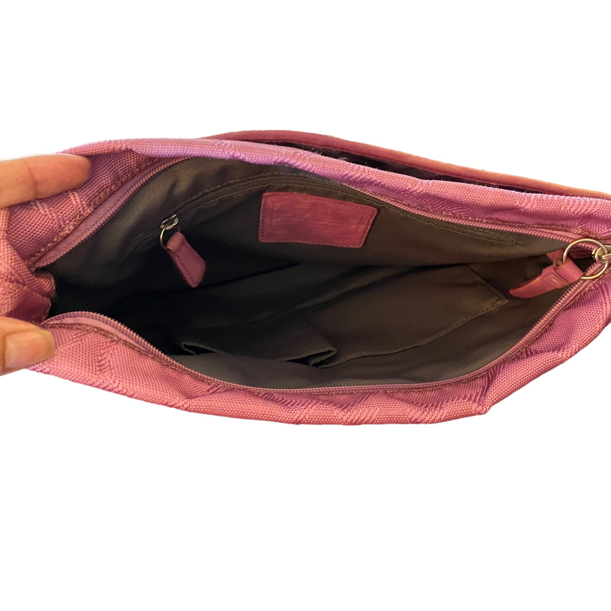 Top view of a purple purse open from the top view with a hand holding the left edge against a white background.