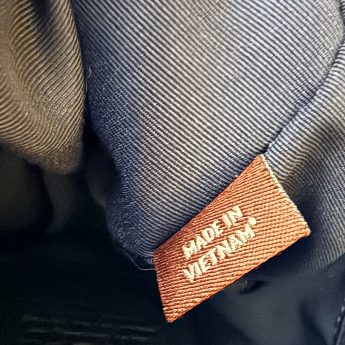 Close-up of black interior  with an orange woven label reading 'MADE IN VIETNAM'.