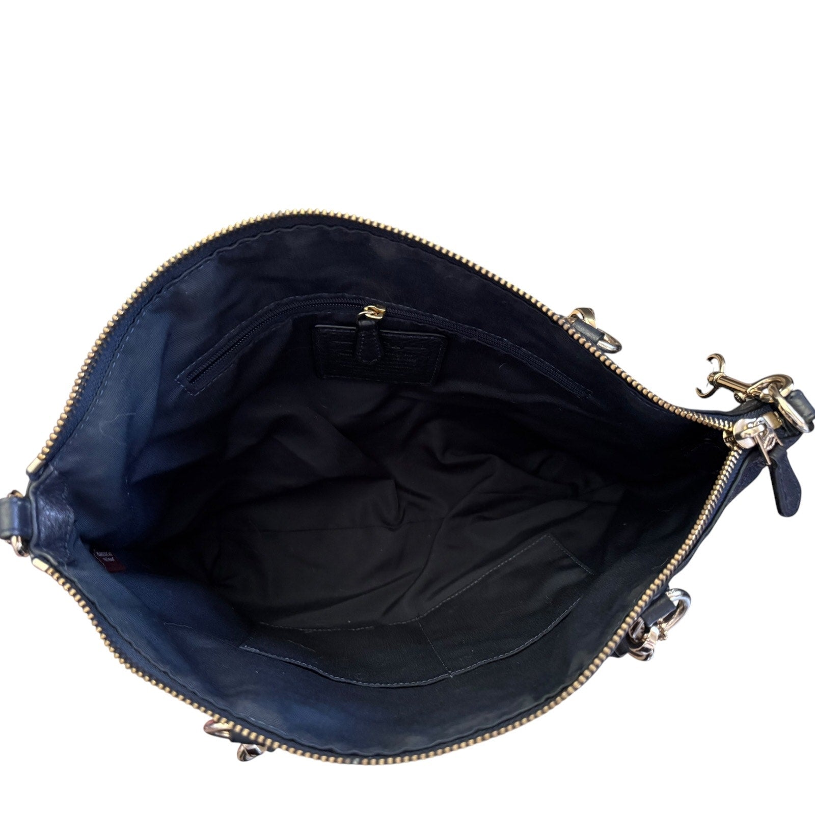 The interior of a black leather handbag shown open against a white background, featuring a black fabric lining, a zippered pocket, and silver-tone metal hardware.