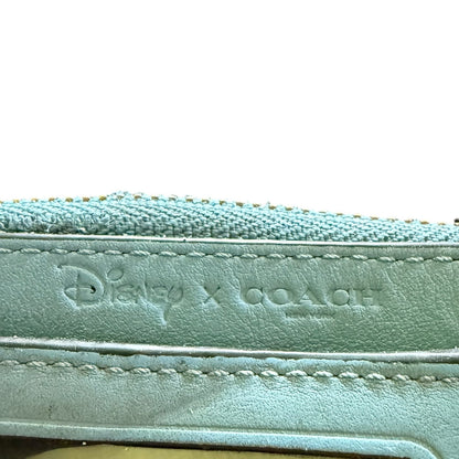 Close-up of a light blue leather product with 'Disney x Coach' branding.