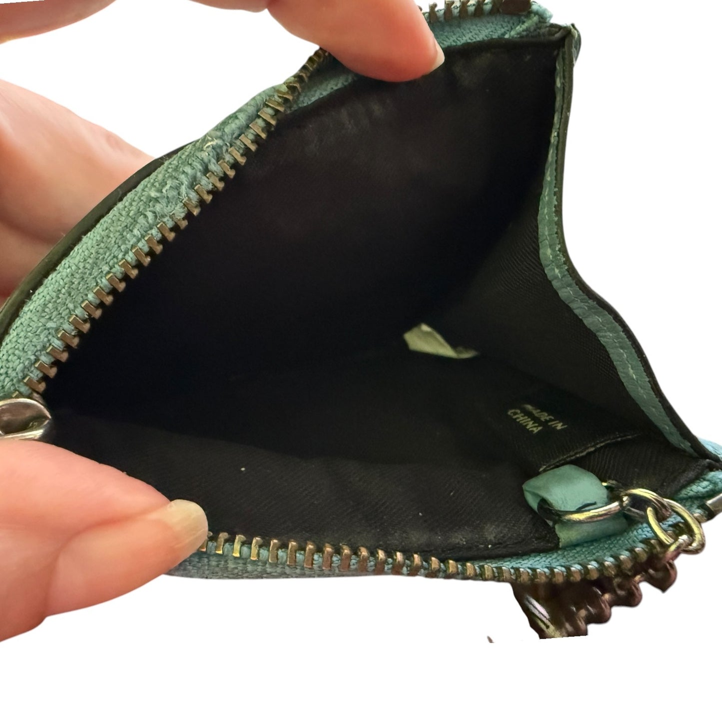 Blue leather pouch with a zipper, held open by hands on a white background