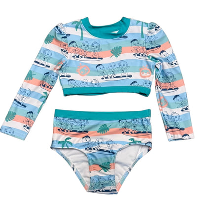 A two-piece children's swim set featuring a long-sleeve crop top and matching bikini briefs. The set has a white base with horizontal stripes in light blue and peach, decorated with a Cocomelon surfing pattern, teal trim, and small palm tree motifs.