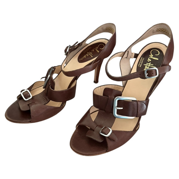 Pair of brown high-heeled sandals with buckles on a white background