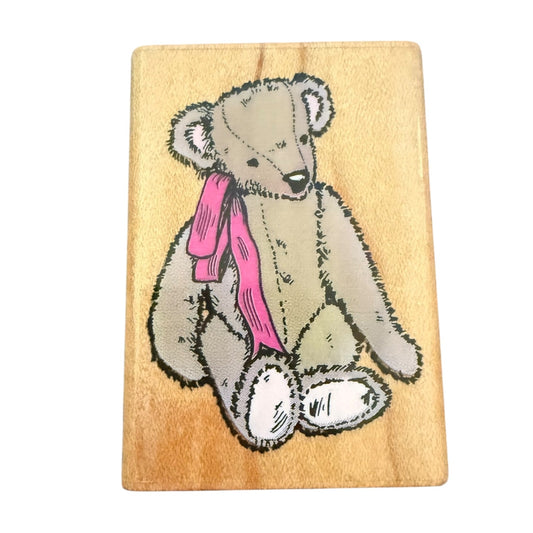 Wooden block with a teddy bear and pink bow design on a white background