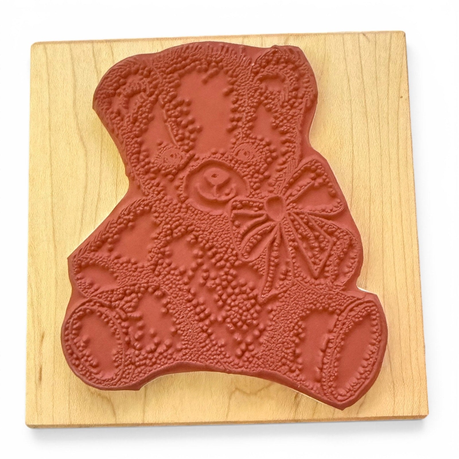 Red rubber stamp shaped like a bear on a wooden board