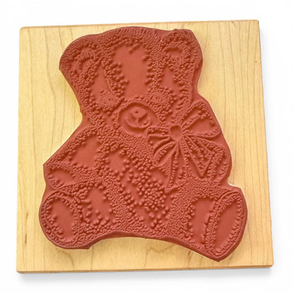Red rubber stamp shaped like a bear on a wooden board