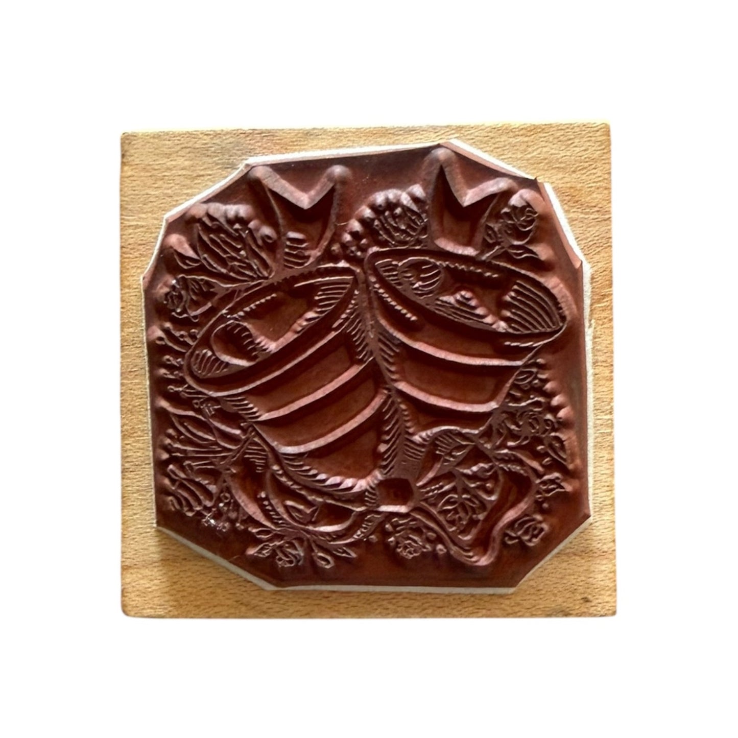 Decorative wooden block with a bells and flower design on a white background