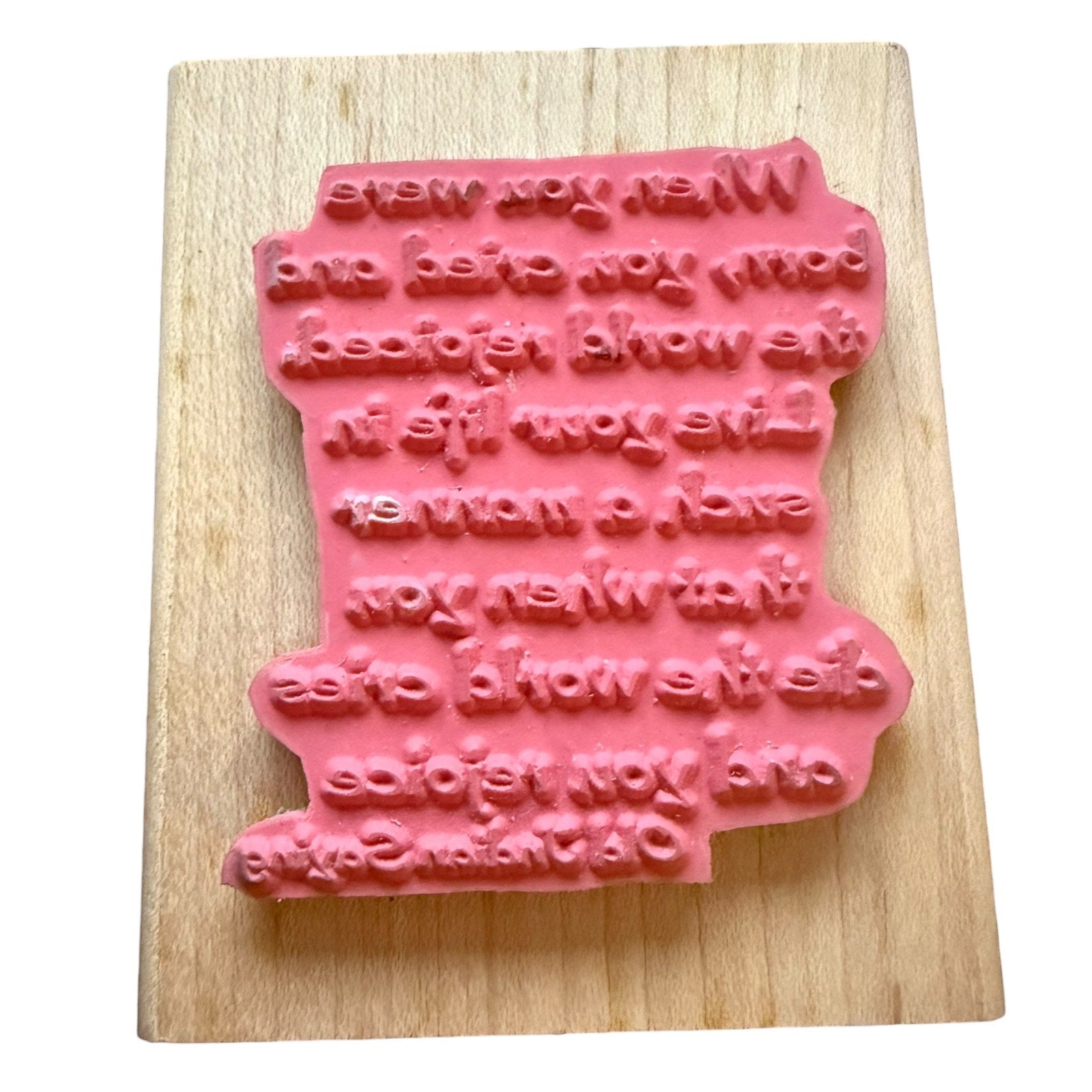Pink rubber stamp block with text on a wooden base