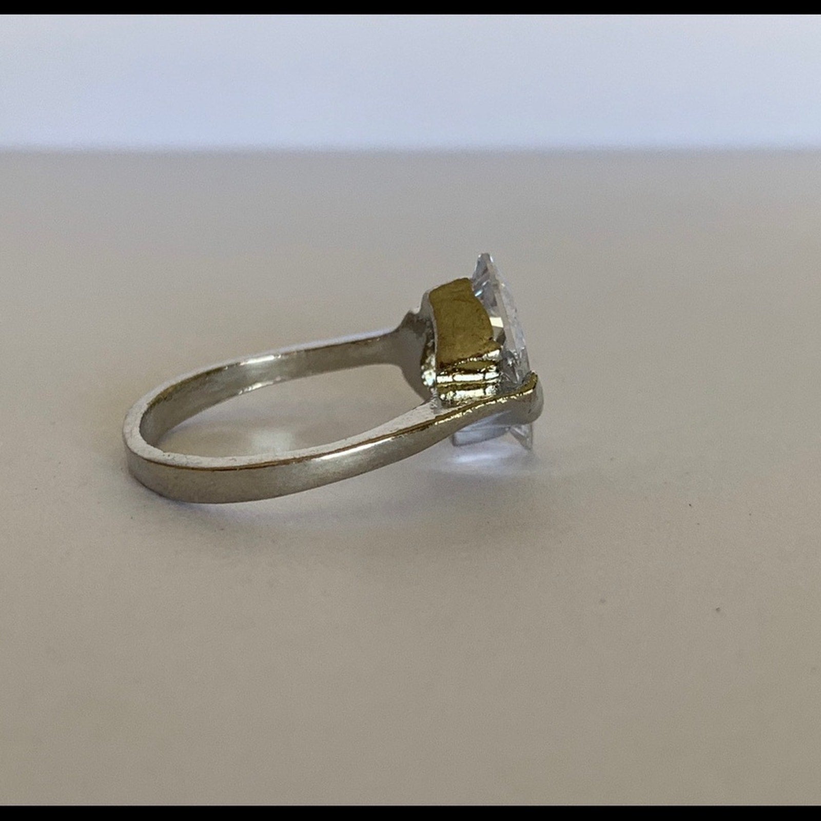 Side view of faux diamond ring on a light background