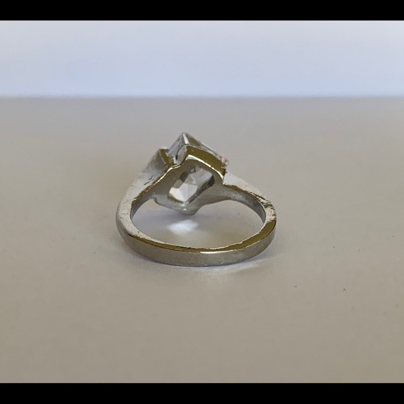 Back of Silver ring with a large faux diamond on a beige background