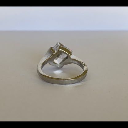 Back of Silver ring with a large faux diamond on a beige background