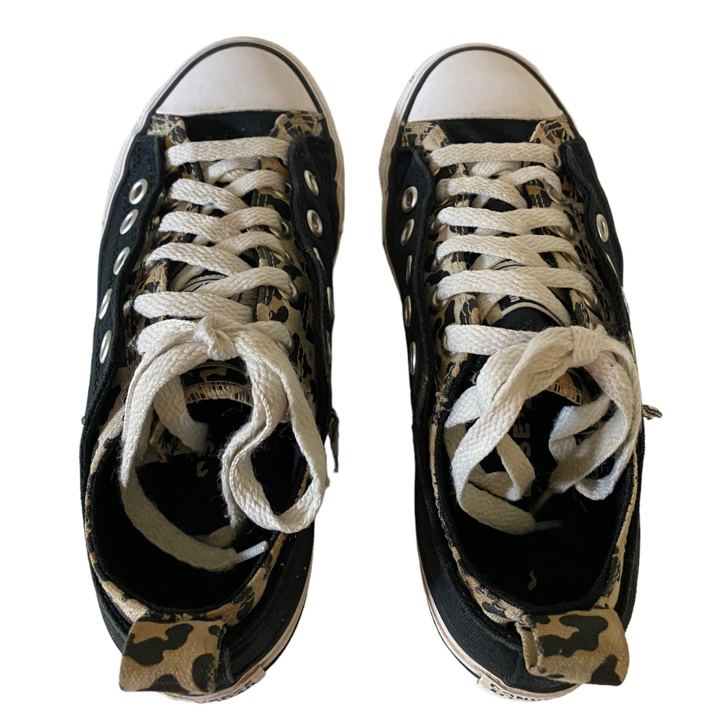 Pair of black low-top sneakers with white laces and animal pattern on a white background