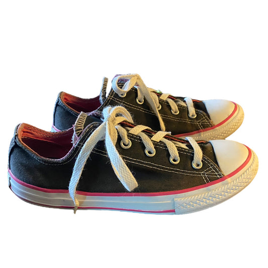 Front side Pair of black sneakers with white laces and pink trim on a white background