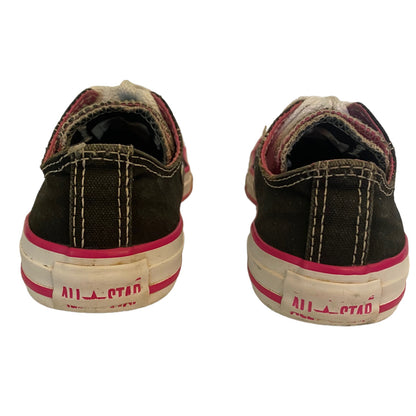 Back of black converse sneakers showing use and wear with pink trim on a white background