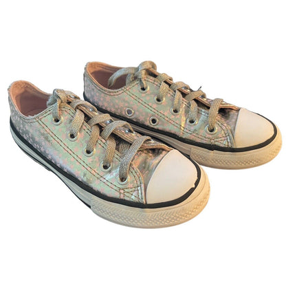 A pair of low-top canvas sneakers with an iridescent, holographic finish. The shoes feature off-white rubber toe caps and soles, black rubber trim, and matching metallic laces, shown against a plain white background.