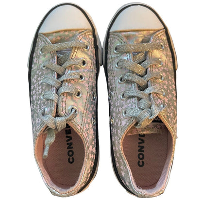 A pair of Converse low-top sneakers with a metallic silver and pink holographic glitter canvas upper, matching glitter laces, and a white rubber toe cap, shown from a top-down view on a white background.