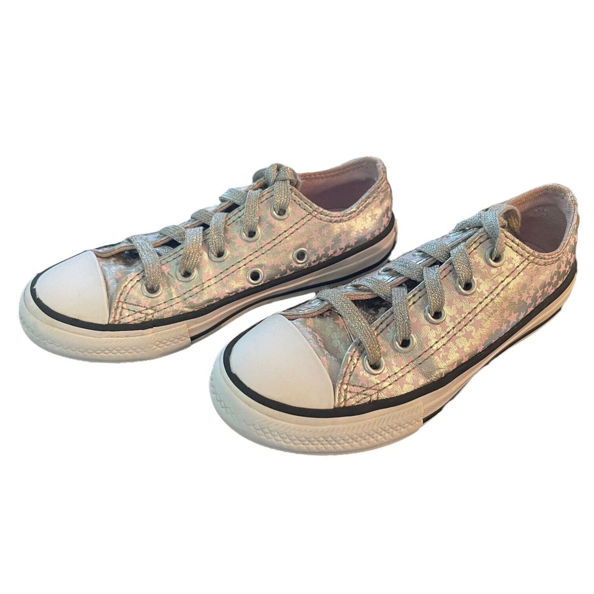 A pair of low-top canvas sneakers with a metallic silver and pink glittery pattern, white rubber toe caps, and white laces, shown on a plain white background.