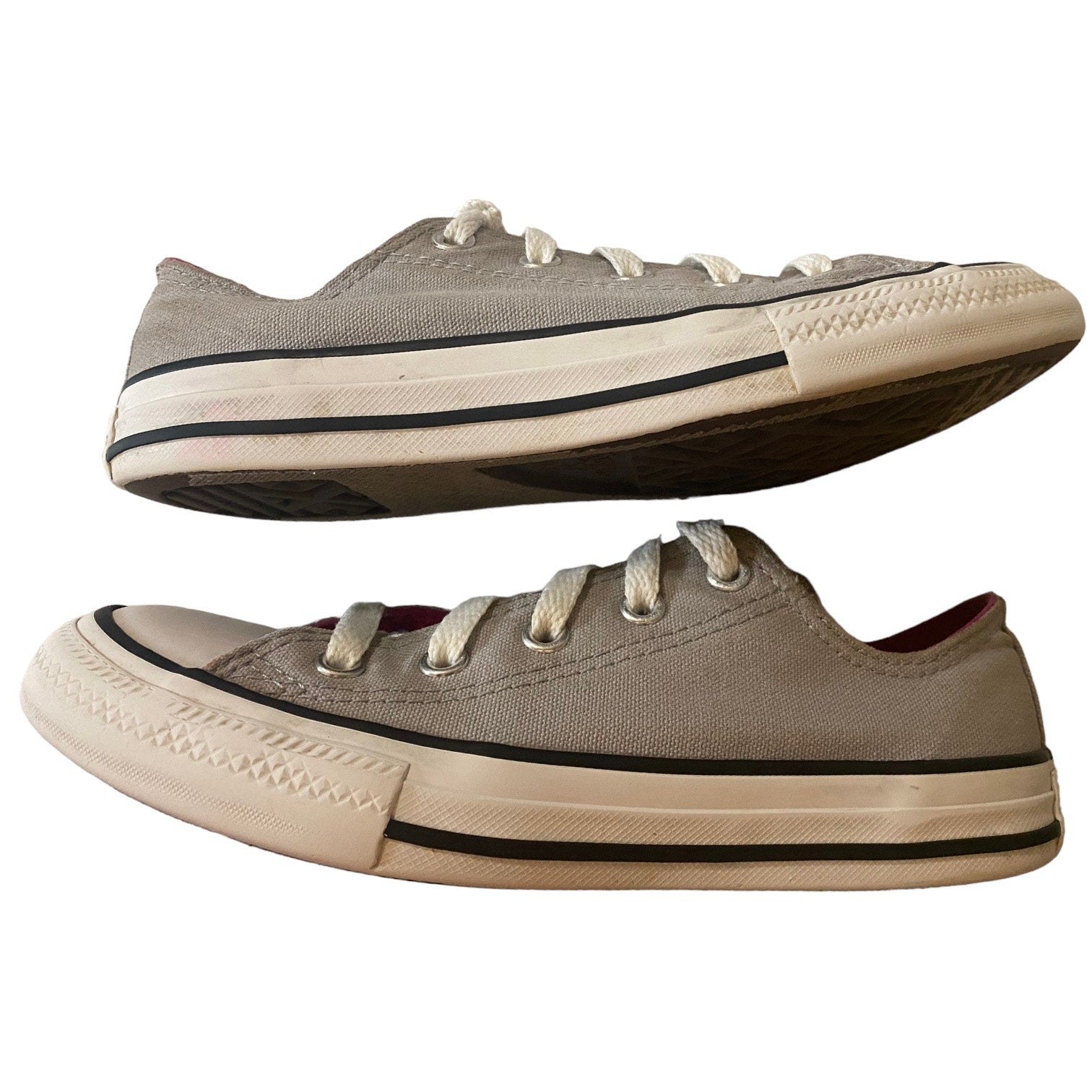 A pair of classic low-top canvas sneakers in a gray color, featuring white laces, a black stripe detail on the midsole, and a cream-colored rubber toe cap and sole.
