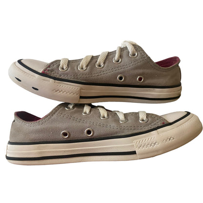 A pair of low-top canvas sneakers in a gray color, featuring white laces.