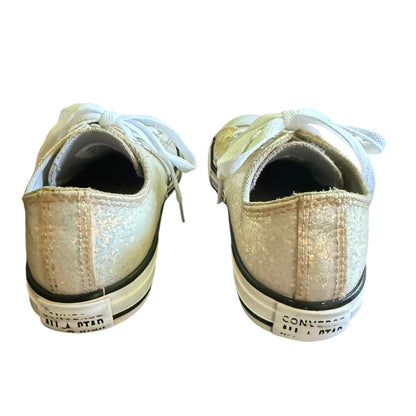 A pair of Converse All Star low-top sneakers shown from the back, featuring a metallic  glitter canvas upper, white laces, and a black and white rubber sole.