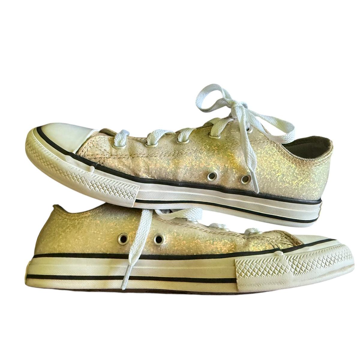 A pair of low-top canvas sneakers covered in glitter, featuring white laces, white rubber toe caps, and white midsoles with black trim, set against a plain white background.