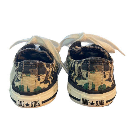 A pair of low-top canvas sneakers shown from the back, featuring a green and black camouflage pattern on the canvas uppers, white laces, and a white rubber sole with 'ONE STAR' branding.