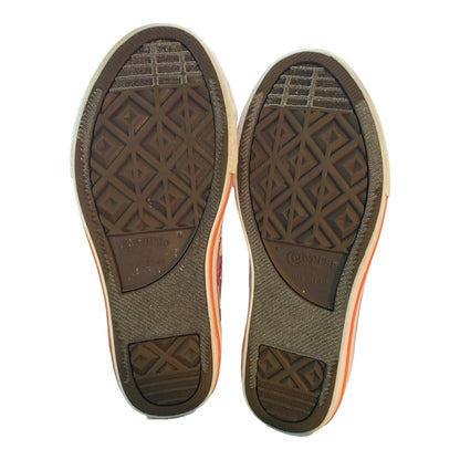 A pair of Converse high-top sneakers shown from the sole view, displaying the textured brown rubber outsoles with the Converse branding and geometric tread patterns.