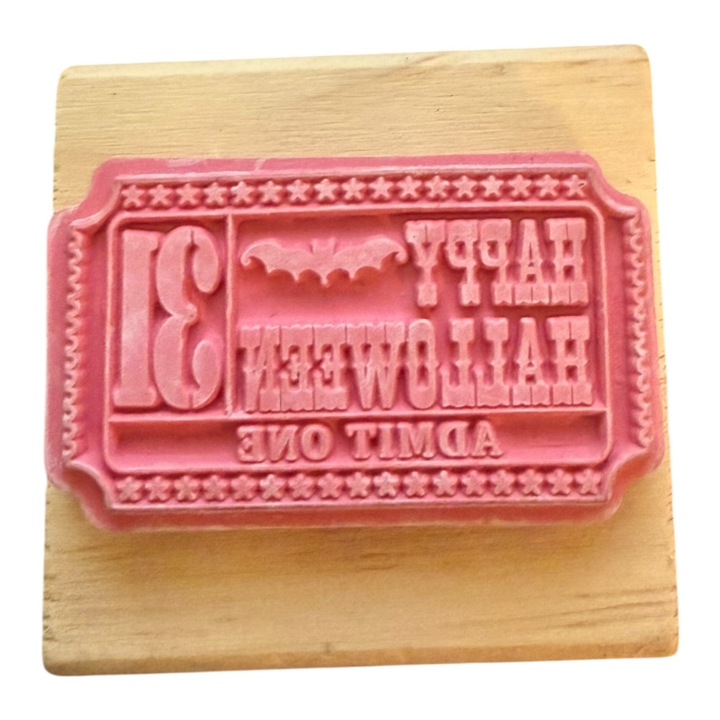 Pink rubber stamp with text on a wooden block