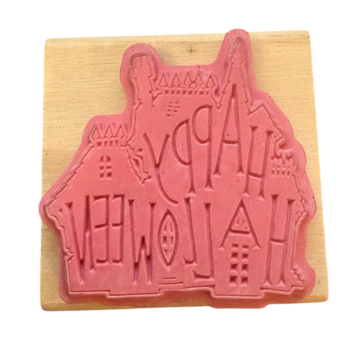 Pink rubber stamp shaped like a house on a wooden block